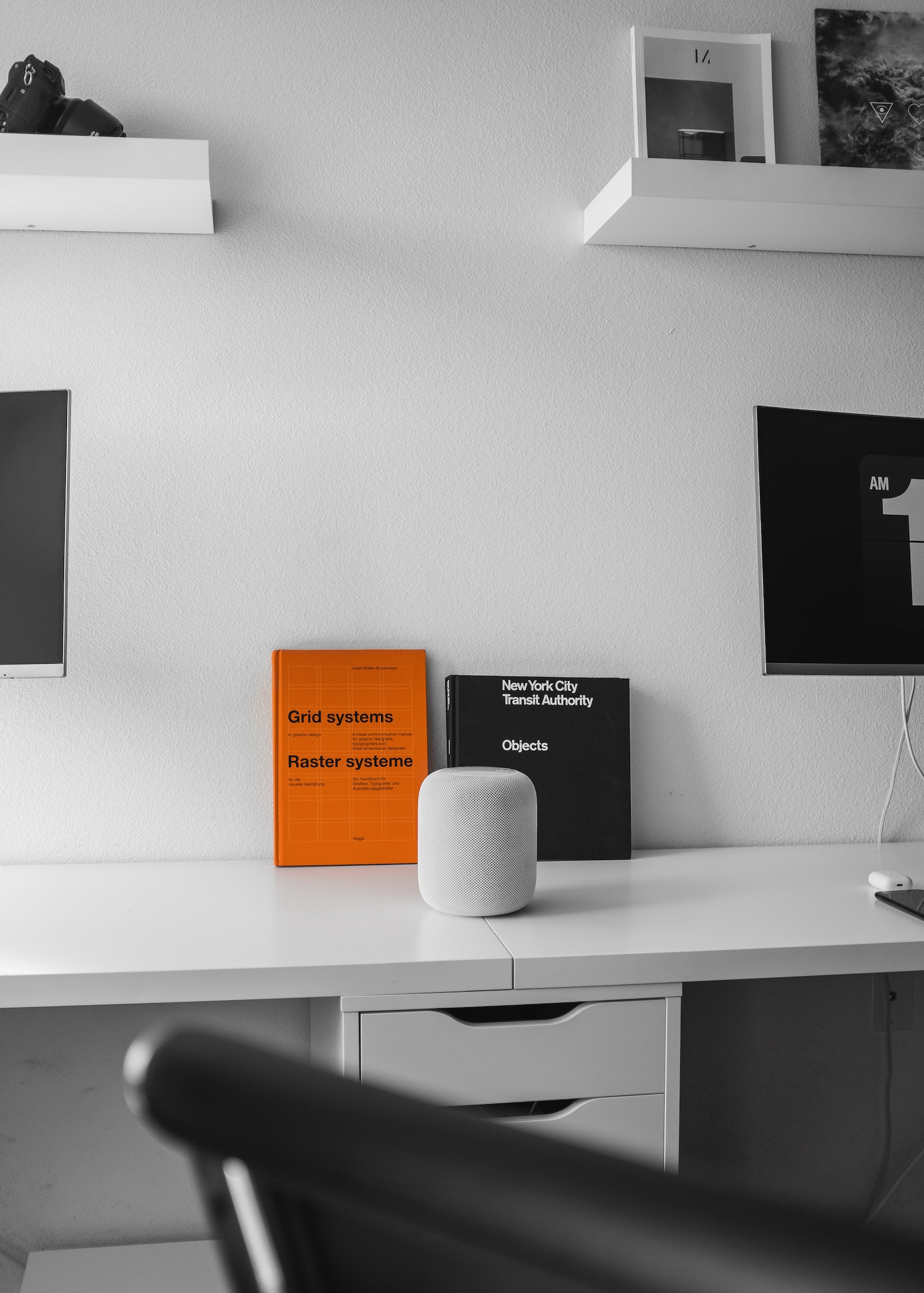 White desk with orange and black books leaning on wall